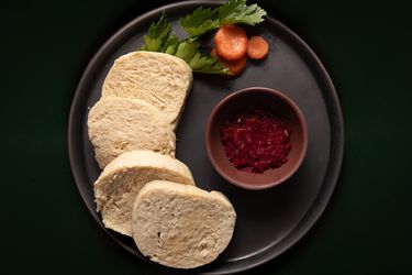 Gefilte fish displayed on a circular plate with red horseradish and garnish