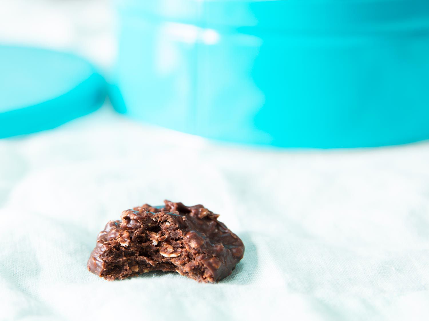 A no-bake cookie lies on a white kitchen towel. A bite reveals the soft, moist interior.