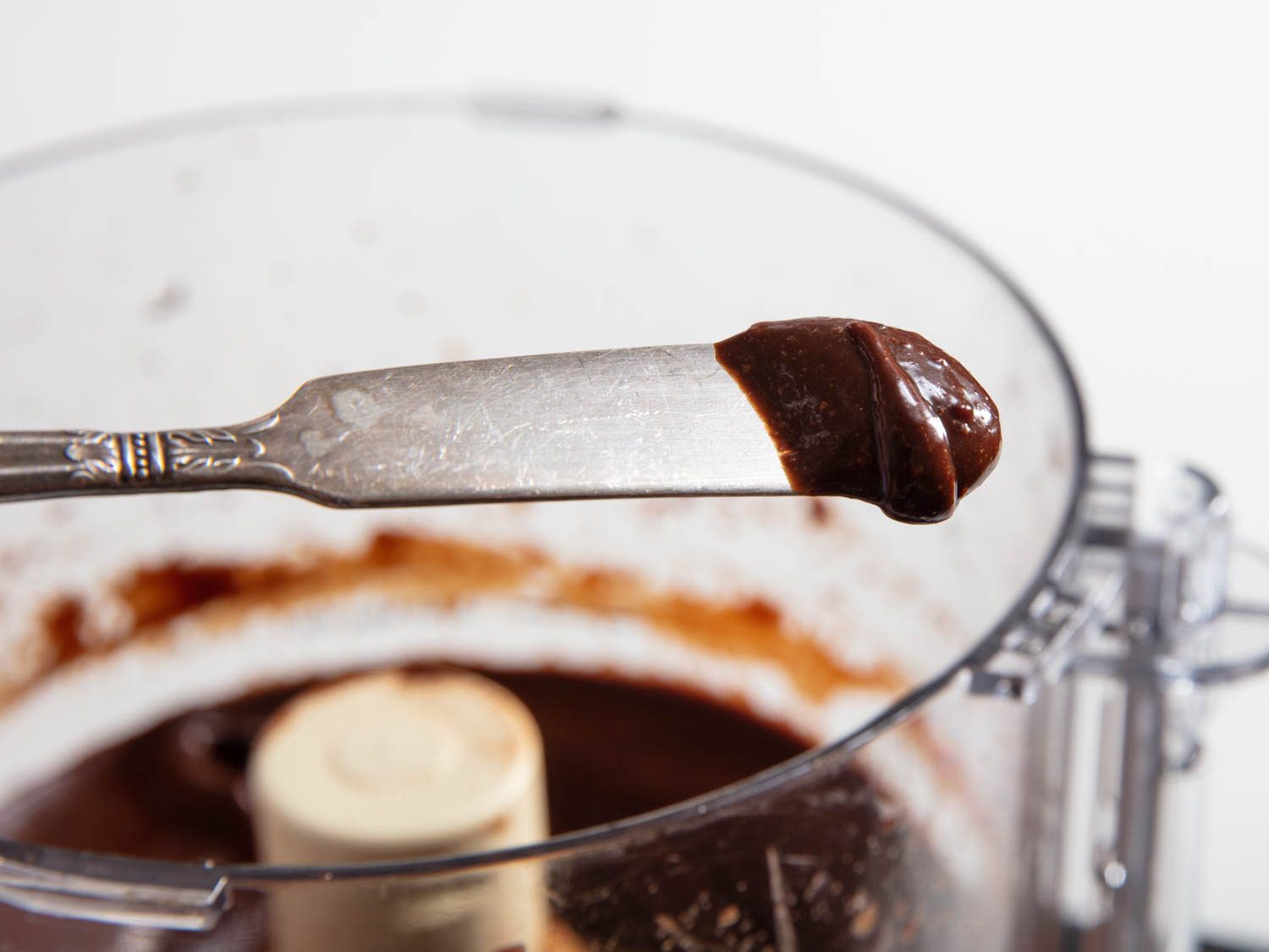 一把刀把奶油榛子巧克力酱(自制的nutella)从食品加工机里拿出来。