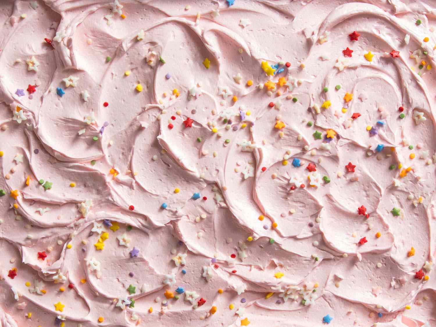 从上到下的视图一个表蛋糕磨砂与粉红色的美国奶油顶部与多色的洒水。gydF4y2Ba