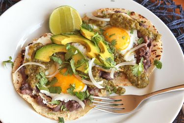 huevos rancheros breakfast tacos topped with sliced avocado