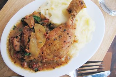 Cider-braised chicken with apples, bacon, and sage plated with mashed potatoes