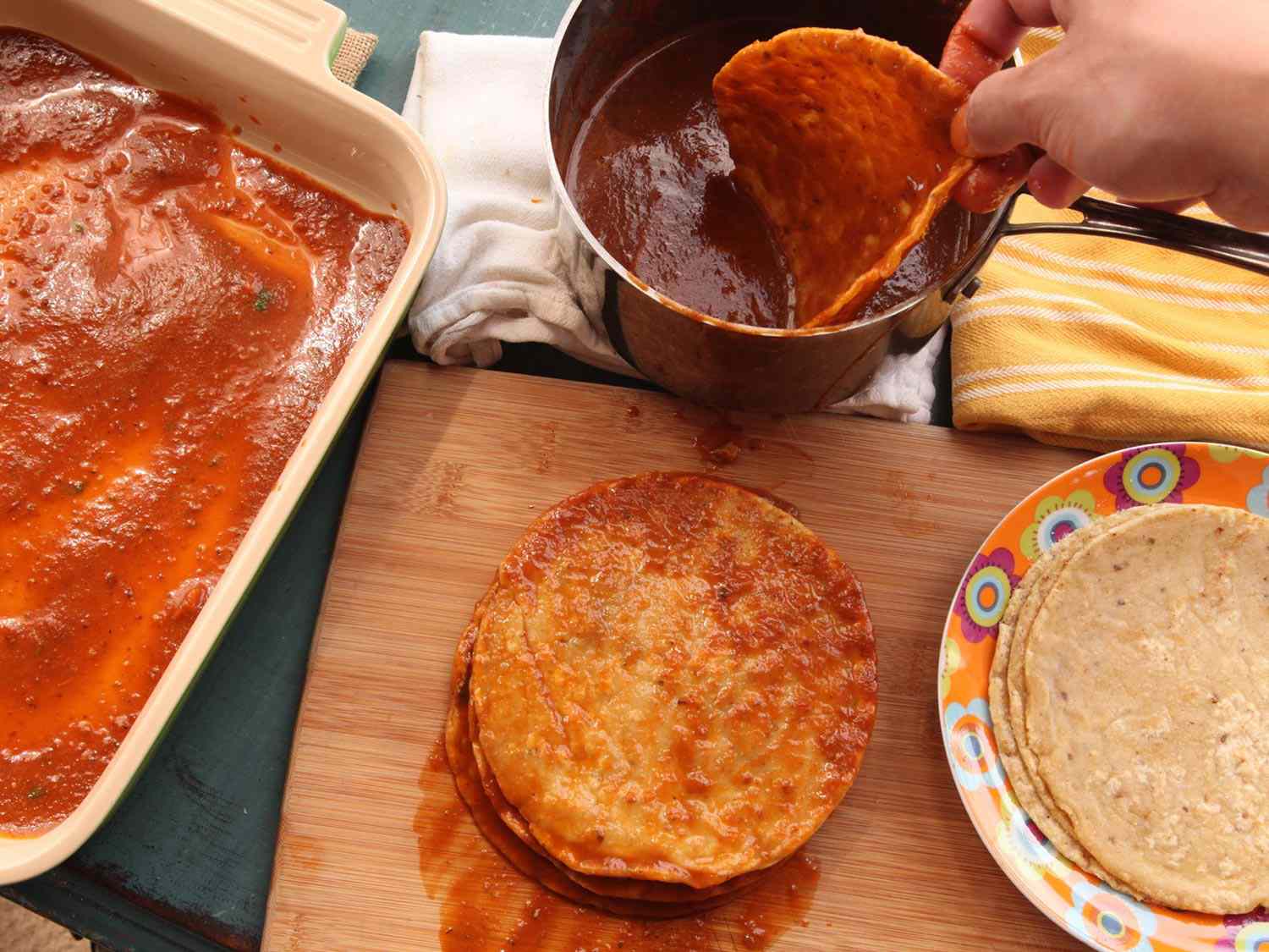 炸好的玉米饼浸在puréed酱汁中，堆叠起来进行最后的组装。