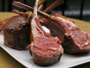 perfect slow-cooked lamb racks arranged standing up on platter