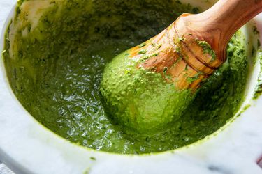 A classic Genovese-style pesto sauce made in a granite mortar with a wooden pestle.