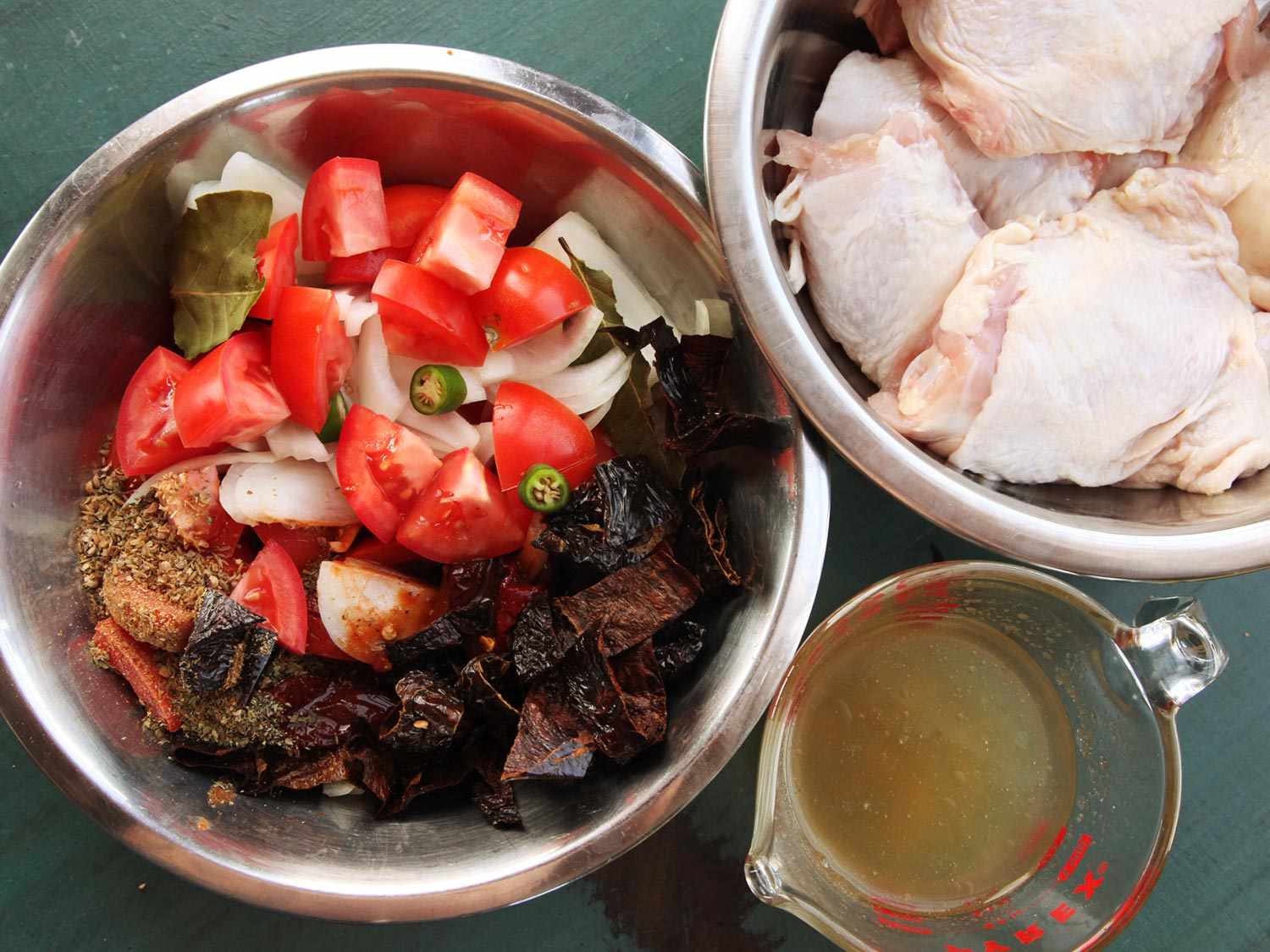 玉米卷饼配料的俯视图:一量杯的高汤，一碗生鸡肉块，一碗开云体育波胆蔬菜，辣椒和调味料。