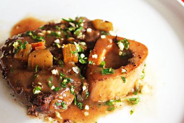 A serving of gravy-covered osso bucco sprinkled with gremolata
