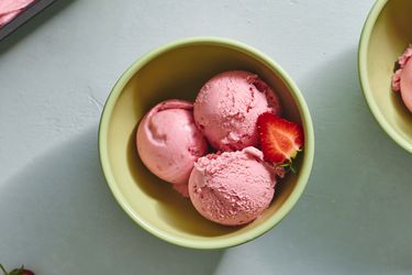 三个陶瓷碗勺草莓冰淇淋,有一半的新鲜草莓。