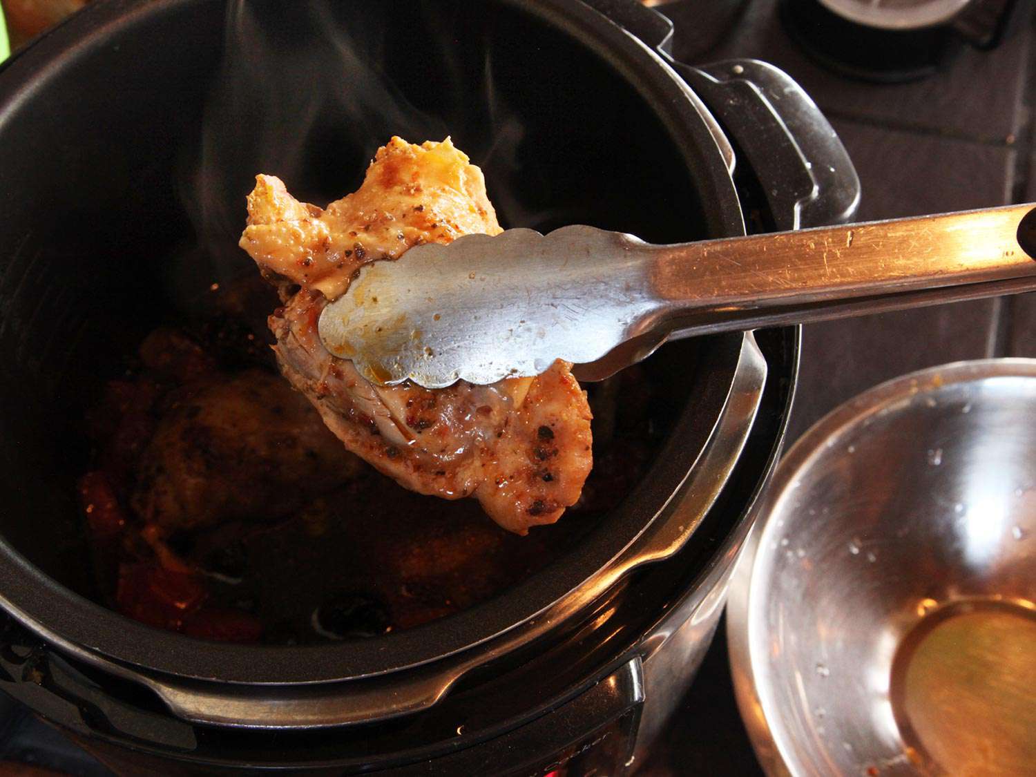 用钳子将炖好的鸡腿从高压锅中取出。