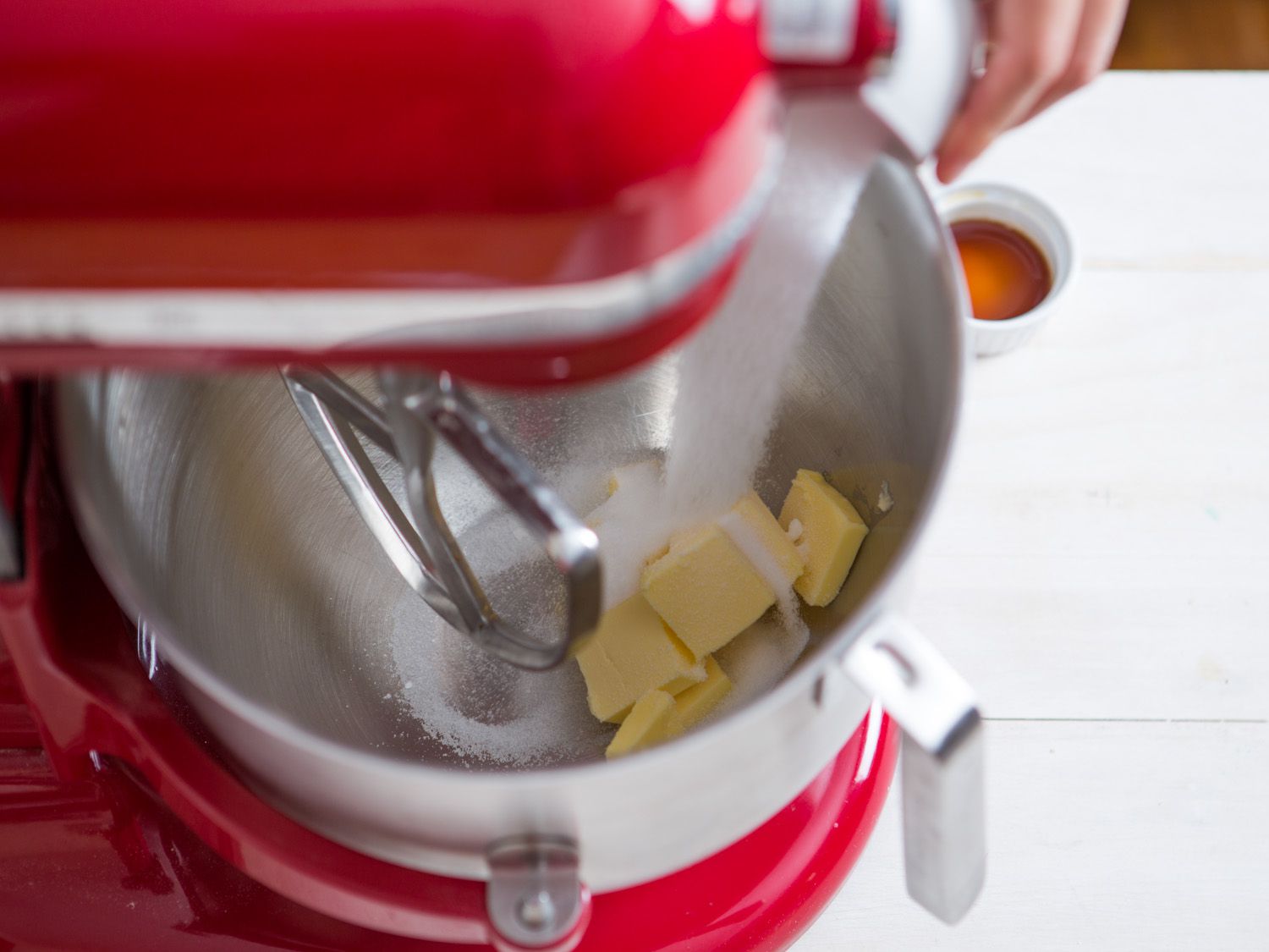 在红色搅拌器的碗里，向黄油中加入糖