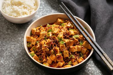 A bowl of spicy mapo tofu with a side of rice