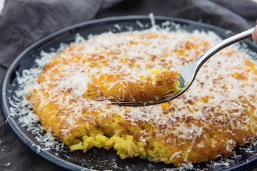 taking a forkful of risotto al salto pancake dusted with grated parmigiano