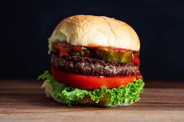 A burger with lettuce, tomato, pickles, and a vegan patty.