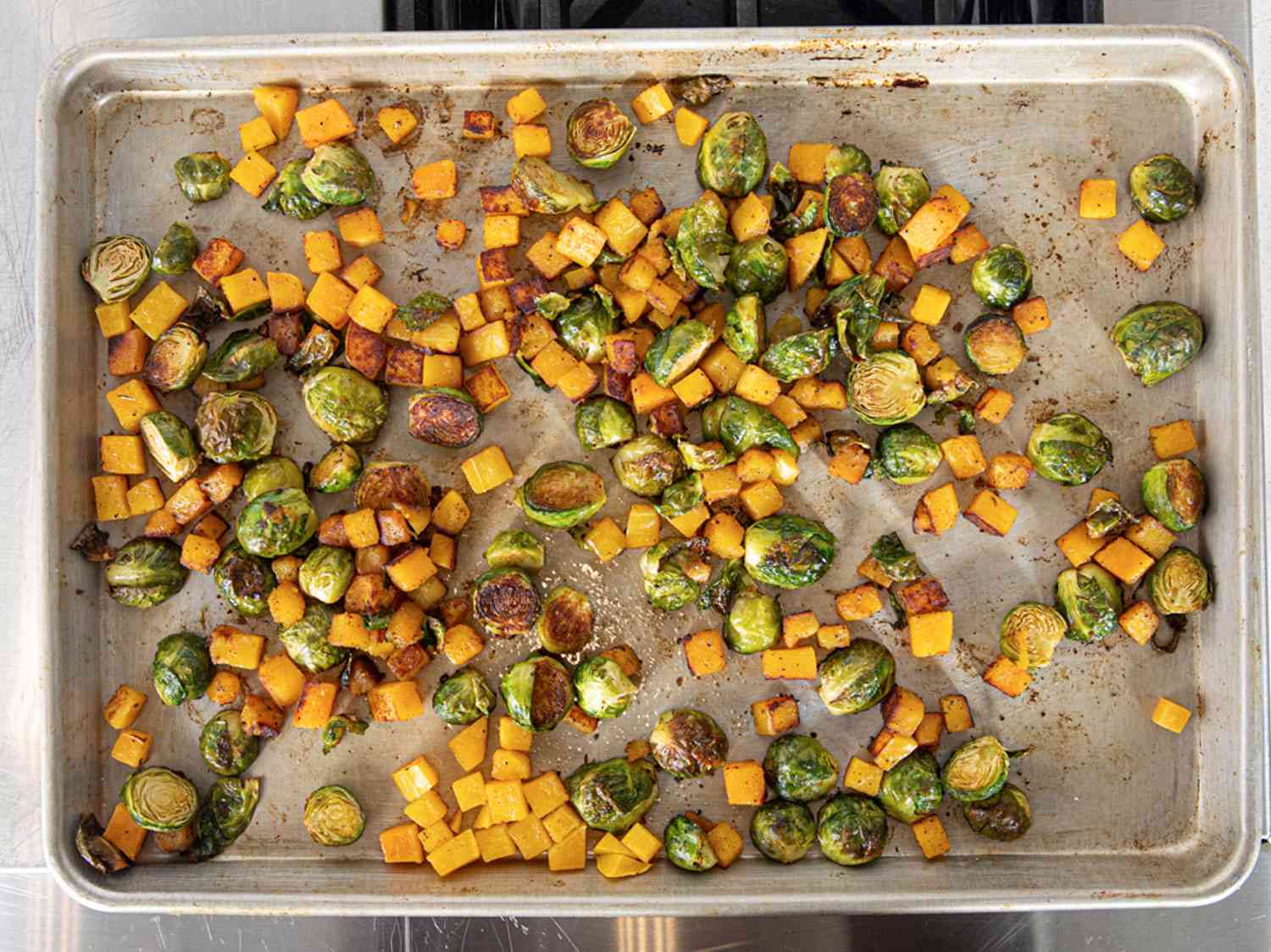 Roasted brussel sprouts and butternut squash on a baking sheet