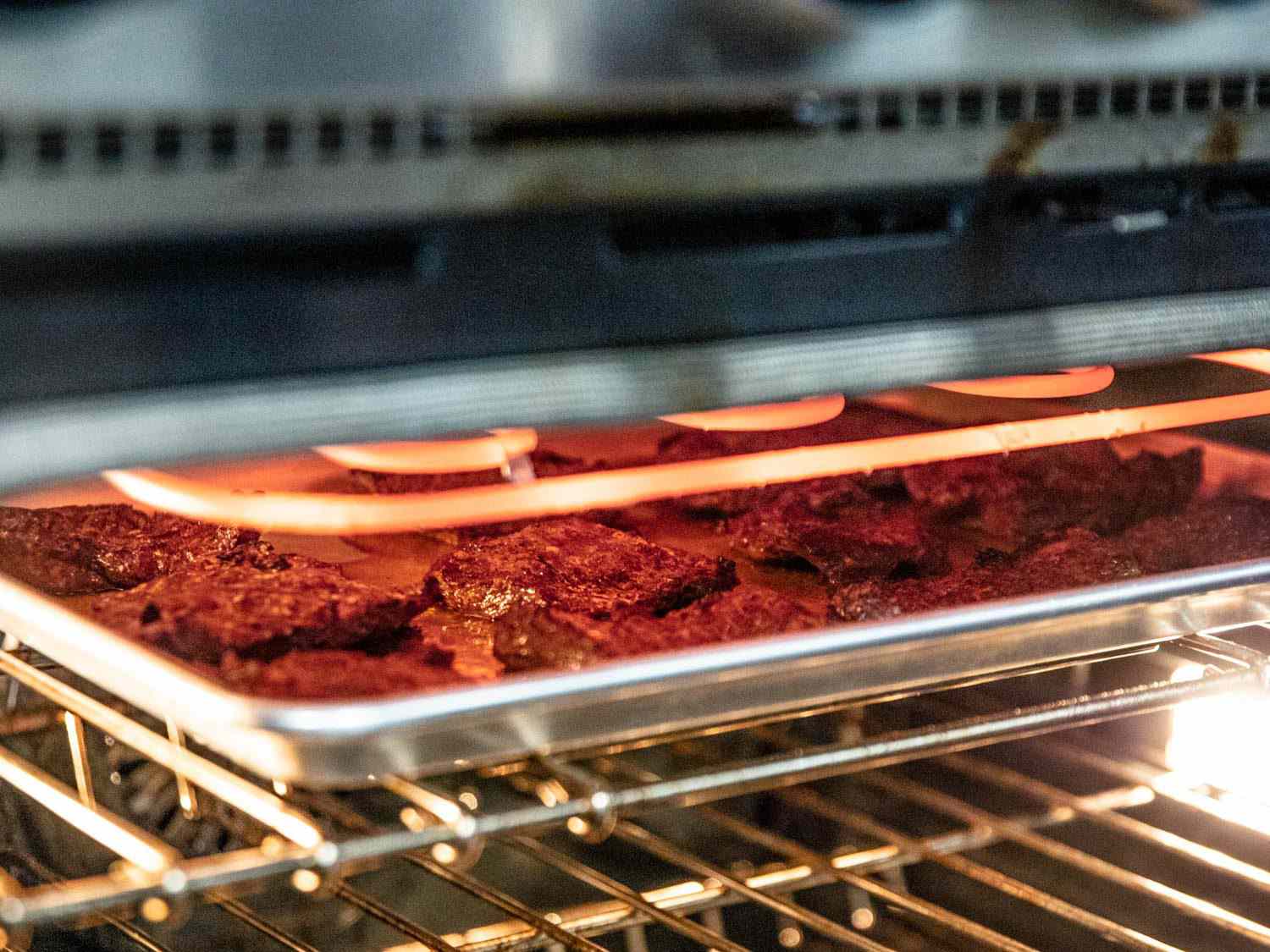 把牛排放在有边的烤盘上，放在烤箱的热烤炉下;烤箱架在最高的位置