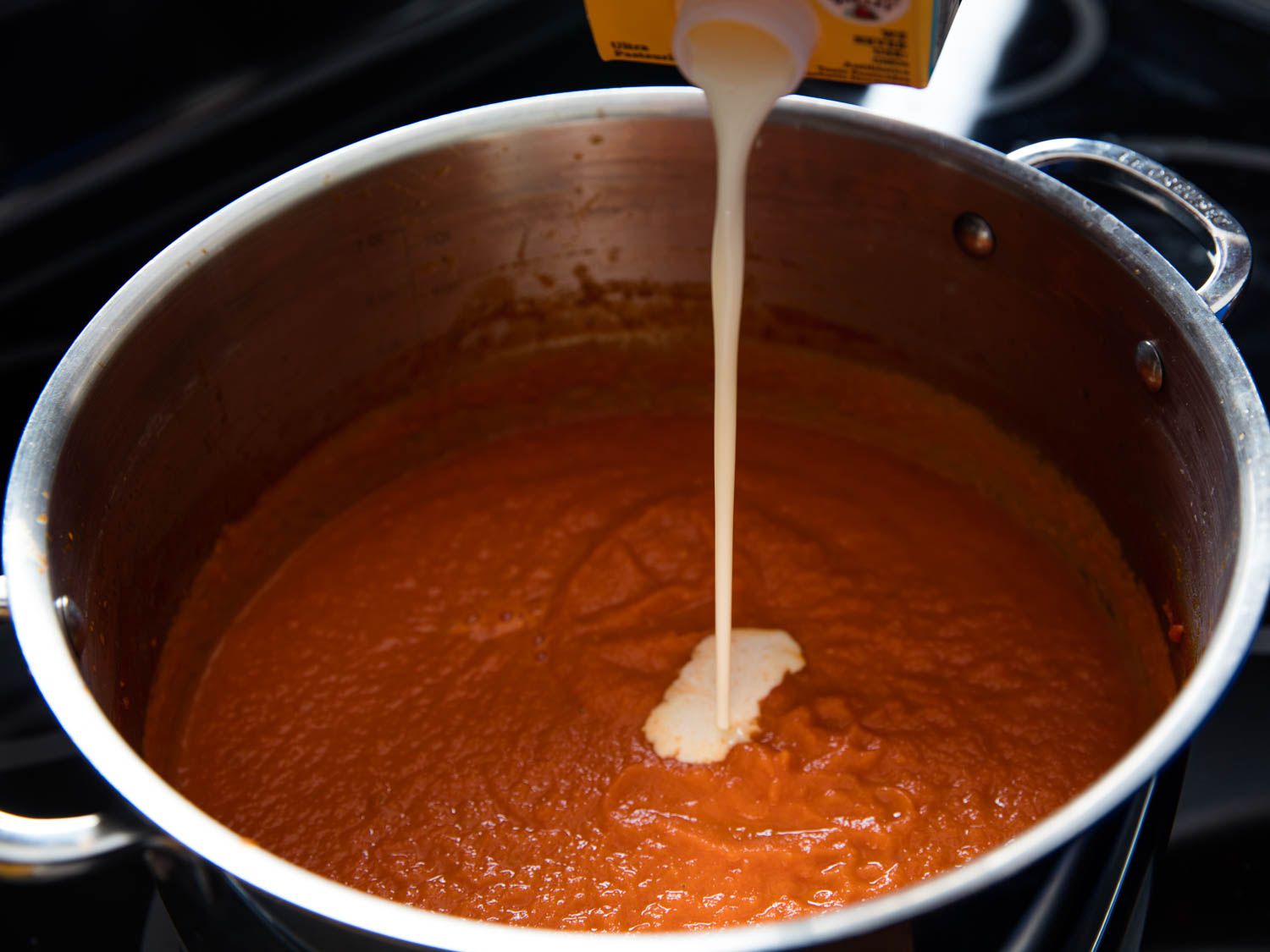 Adding cream to tomato purée for tomato soup